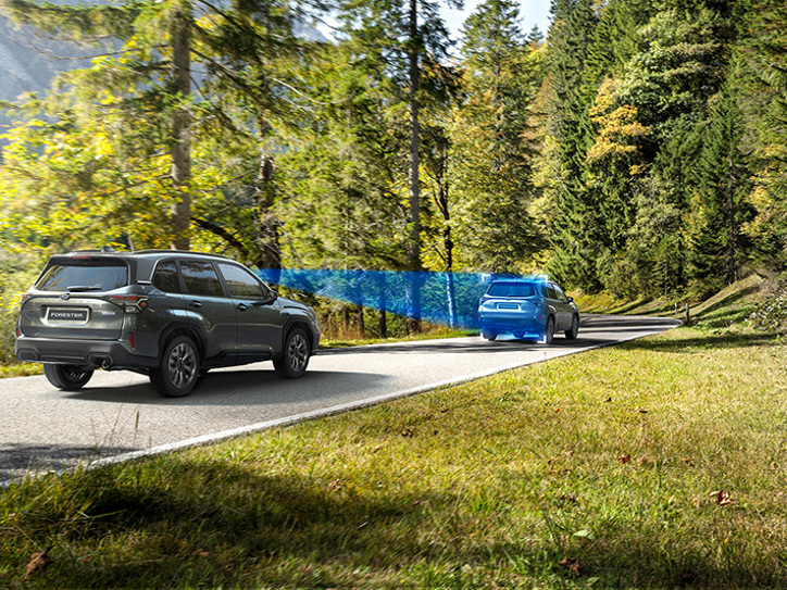 Subaru Forester ajaa tiellä, ja sininen kolmionmuotoinen kuvitus näyttää auton EyeSight-kameroiden näkökentän.
