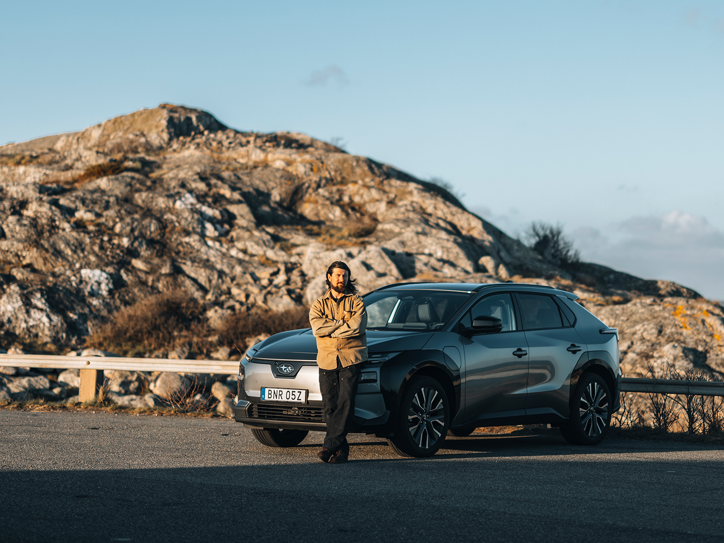 Subaru Solterra pysäköitynä kallioiseen maisemaan henkilön seistessä auton edessä.